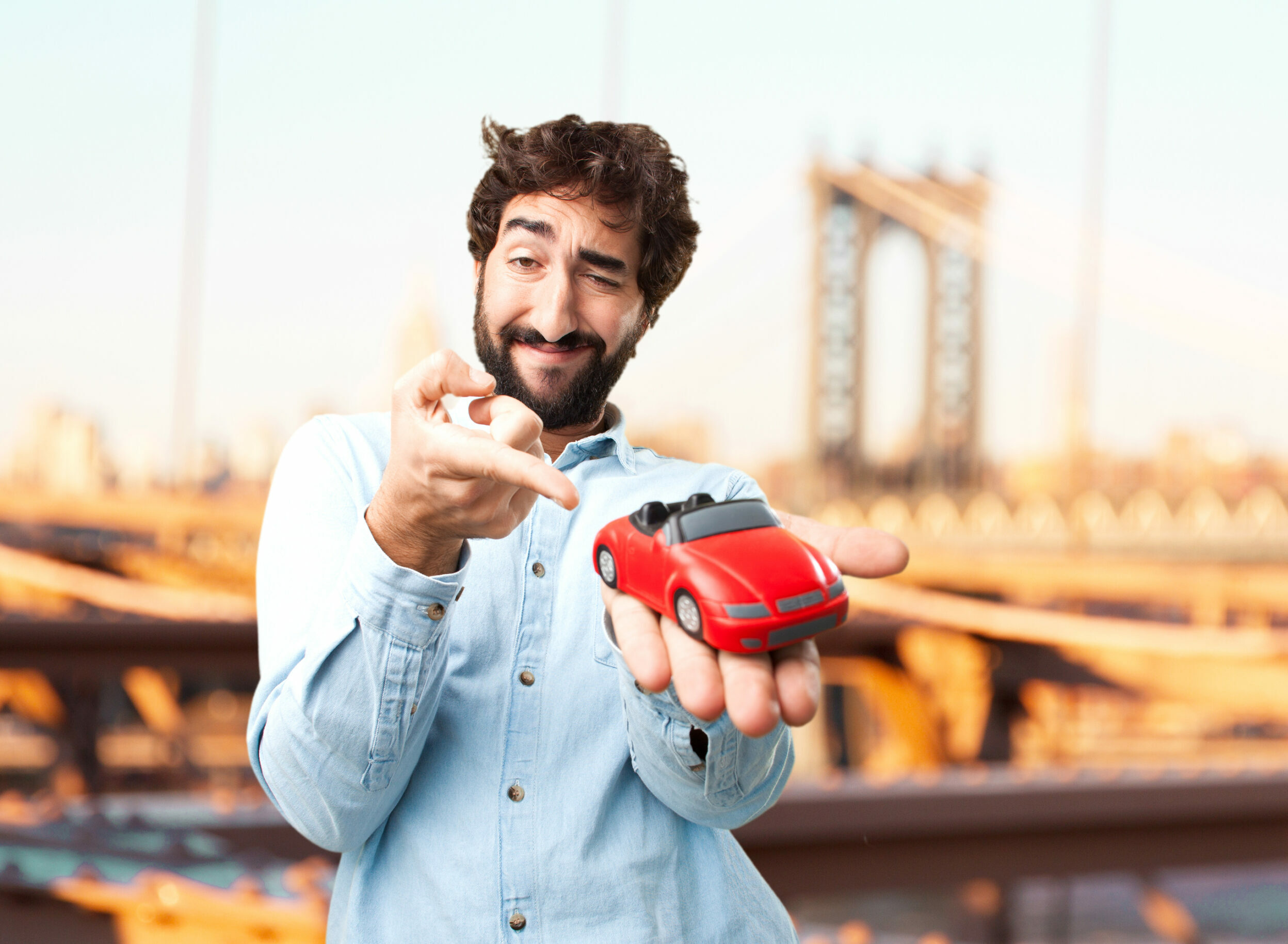 Jeune homme tenant une voiture rouge dans sa main
